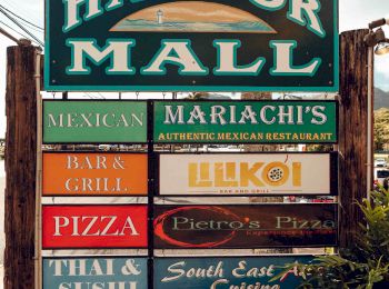 A sign for Harbor Mall with listings for various restaurants including Mexican, Mariachi's, Bark Grill, Lilikoi, Pietro's Pizza, Thai & Sushi, and South East Cuisine.